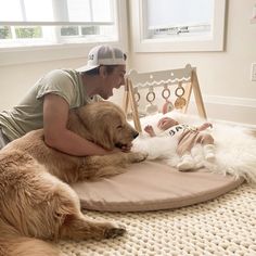 a woman is petting a baby on the bed with her large brown dog next to it