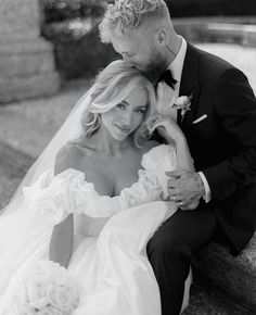 black and white photo of bride and groom sitting on stone steps with bouquet in hand