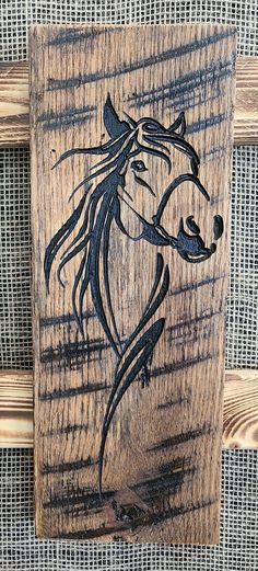 a wooden sign with a horse drawn on it's face and manes in black ink