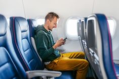 a man sitting on an airplane looking at his cell phone