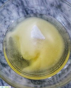 a glass bowl filled with liquid on top of a marble countertop next to a white and yellow substance