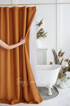 a woman standing behind a curtain in front of a bathtub and flower vases