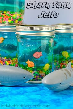 there are many fish in the jar on the table and one shark is next to it