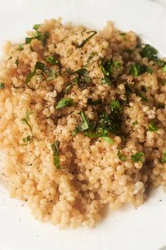 a white plate topped with brown rice and spinach sprinkled with seasoning