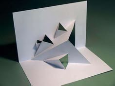 an origami sculpture is displayed on a green surface with white paper folded around it