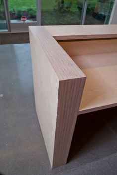 a close up of a wooden shelf with windows in the background