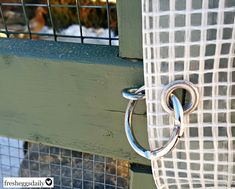 a close up of a metal ring on the side of a green door with a white checkered curtain