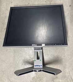 a dell computer monitor sitting on top of a metal stand in front of a wall