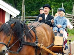 a man and two children are riding on a horse drawn carriage in front of a barn