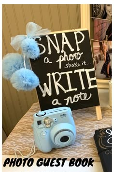 a blue camera sitting on top of a table next to a sign that says snap a photo and write a note