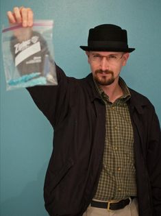 a man wearing a hat and jacket holding up a plastic bag with something in it