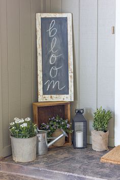 a chalkboard sign sitting on top of a wooden shelf next to potted plants