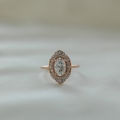 an engagement ring with a diamond center surrounded by small round diamonds on a white background