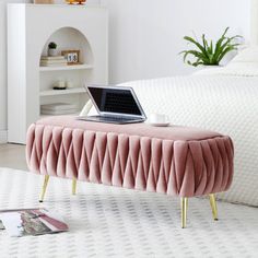 a laptop is sitting on a pink bench in the middle of a white bed room