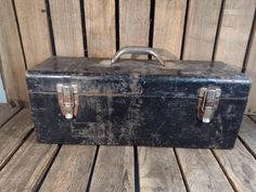 an old black suitcase sitting on top of a wooden floor