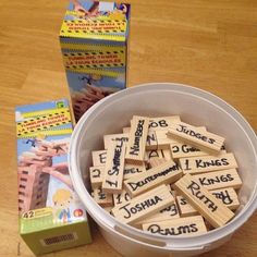 a bucket filled with wooden scrabbles next to a box of children's books