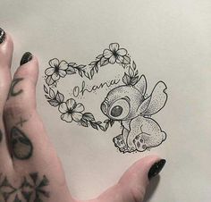 a person's hand holding up a drawing of a koala with flowers on it