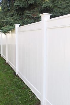 a white fence in the grass next to some trees