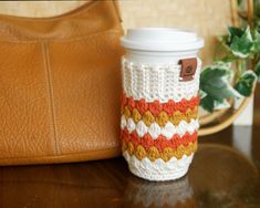 a coffee cup cozying next to a purse