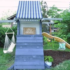 a small wooden structure with a hammock and swing set in the back yard