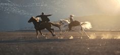 two people riding horses in an open field