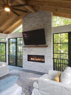 a living room filled with white furniture and a flat screen tv mounted on the wall