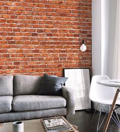 a living room filled with furniture and a brick wall behind the couch is a coffee table