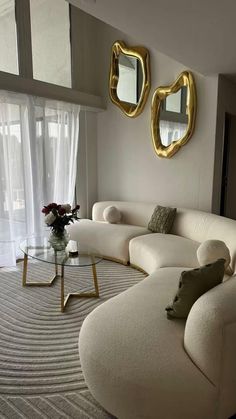 a living room with white couches and gold mirrors