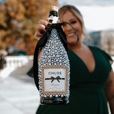 a woman holding up a bottle that has been decorated with pearls and black ribbon around the neck