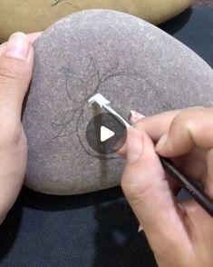 someone is drawing on a rock with a marker