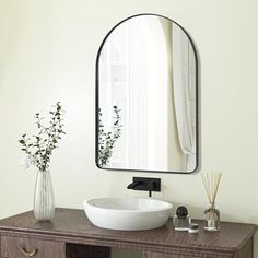 a bathroom with a sink, mirror and flowers on the counter top in front of it