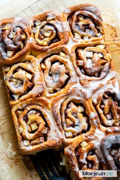 cinnamon rolls with icing sitting on top of a cutting board next to a fork