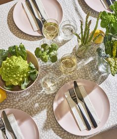 a table topped with pink plates filled with food and veggies next to utensils