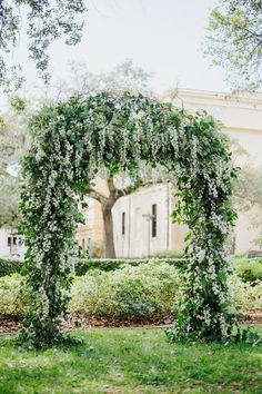 an arch covered in white flowers and greenery