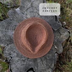 a crochet hat sitting on top of a piece of wood in the grass