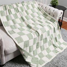 a green and white blanket sitting on top of a couch next to a black table