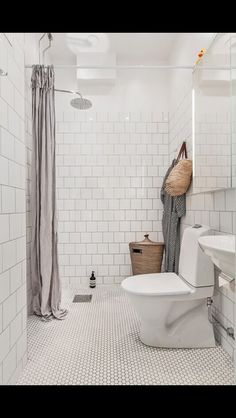 a white bathroom with black and white tile flooring, shower curtain, and toilet