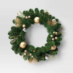 a christmas wreath with ornaments hanging from it's sides and gold balls on top