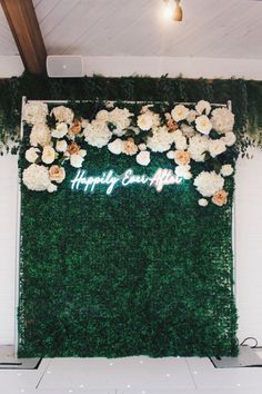 a green wall with white flowers and the words happily married on it's side