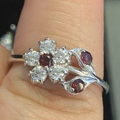 a woman's hand with a ring that has three stones on it and two leaves