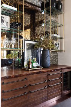 a wooden cabinet with glass shelves and bottles on it, next to a framed photograph