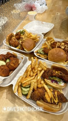 four trays filled with different types of food on top of a wooden table in a restaurant