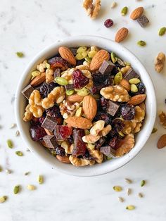 a bowl filled with nuts and raisins on top of a white countertop