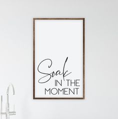 a framed poster hanging on the wall next to a sink and faucet in a bathroom