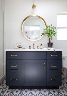 a bathroom with blue and white tile flooring and a round mirror above the sink