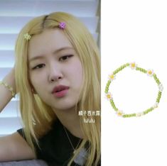 a girl with long blonde hair wearing a green bracelet and flower beaded bracelets