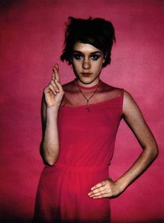 a woman in a red dress posing with her hand on her hip and wearing a choker