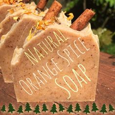 three soap bars sitting on top of a wooden table with cinnamon sticks sticking out of them