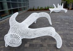 two white sculptures sitting on top of a brick floor next to each other in front of a building