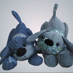 two stuffed dogs are sitting next to each other, one is blue and the other is gray